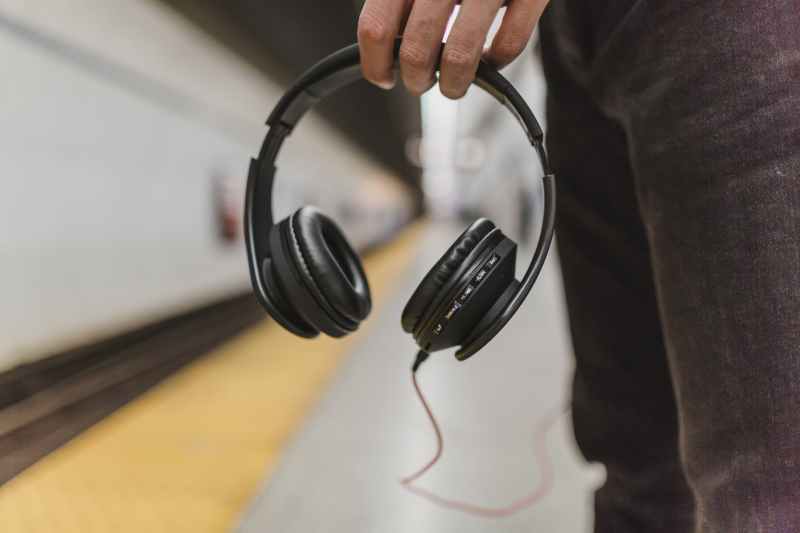 shallow focus photography of person holding headphones